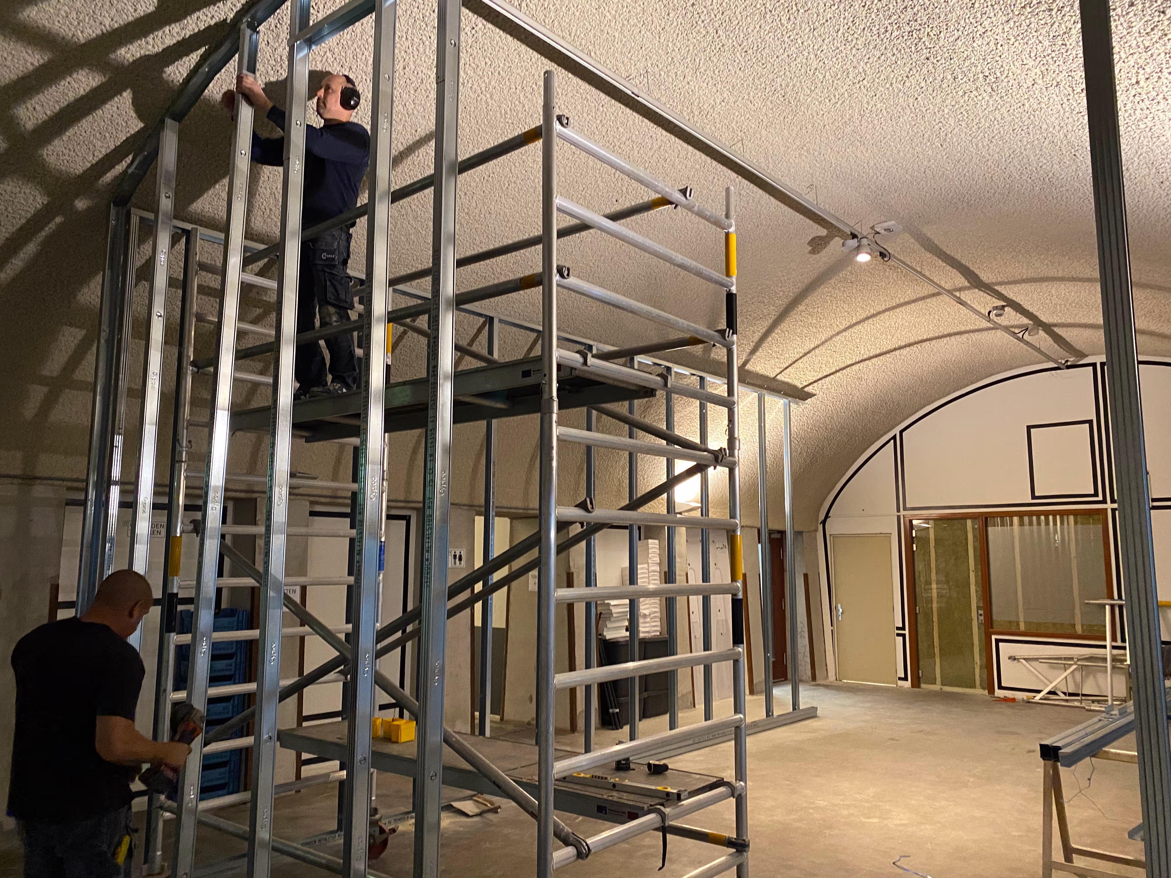 Op een steiger wordt aan het plafond gewerkt