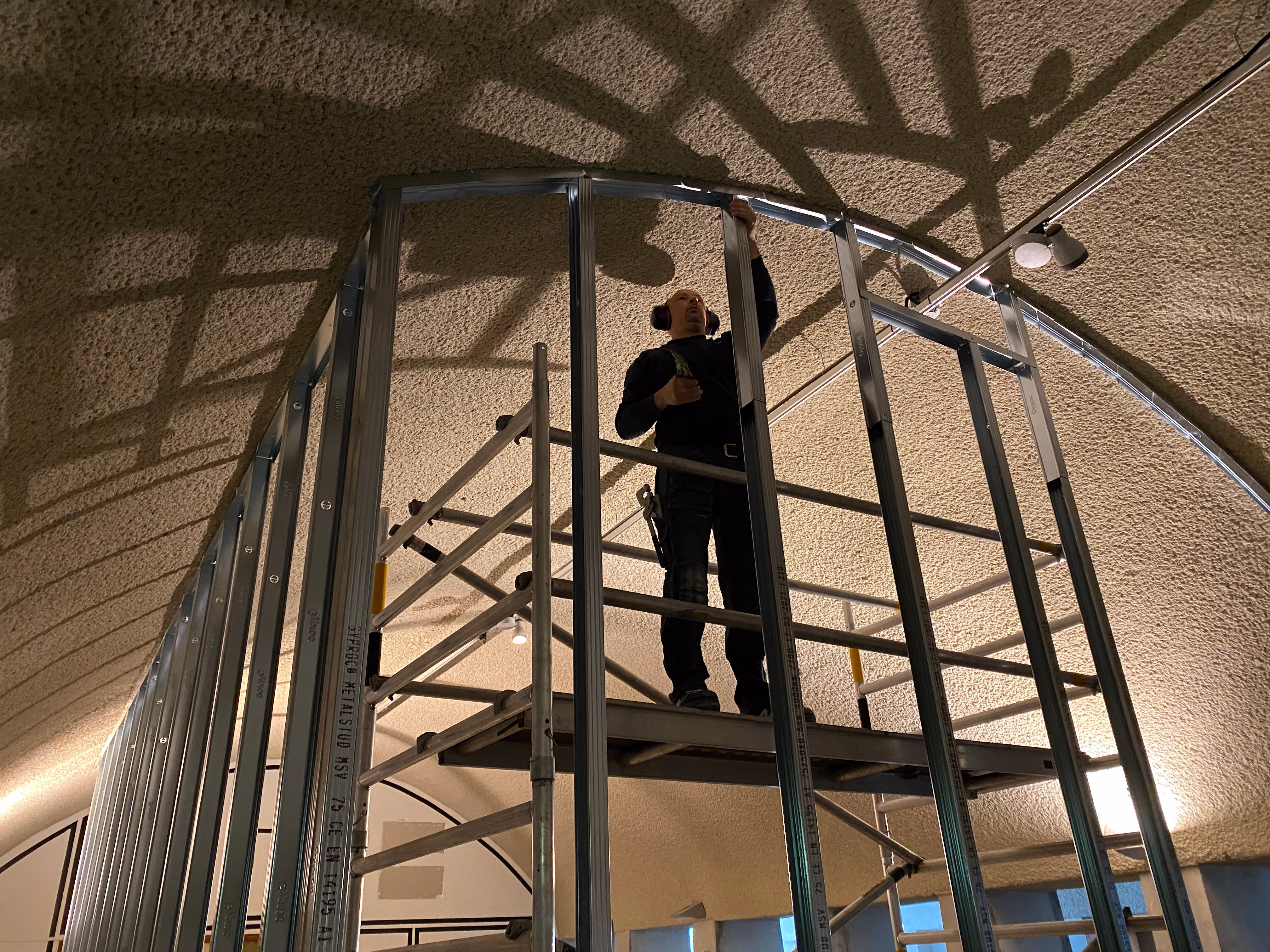 Man staat op een steiger en werkt aan het plafond