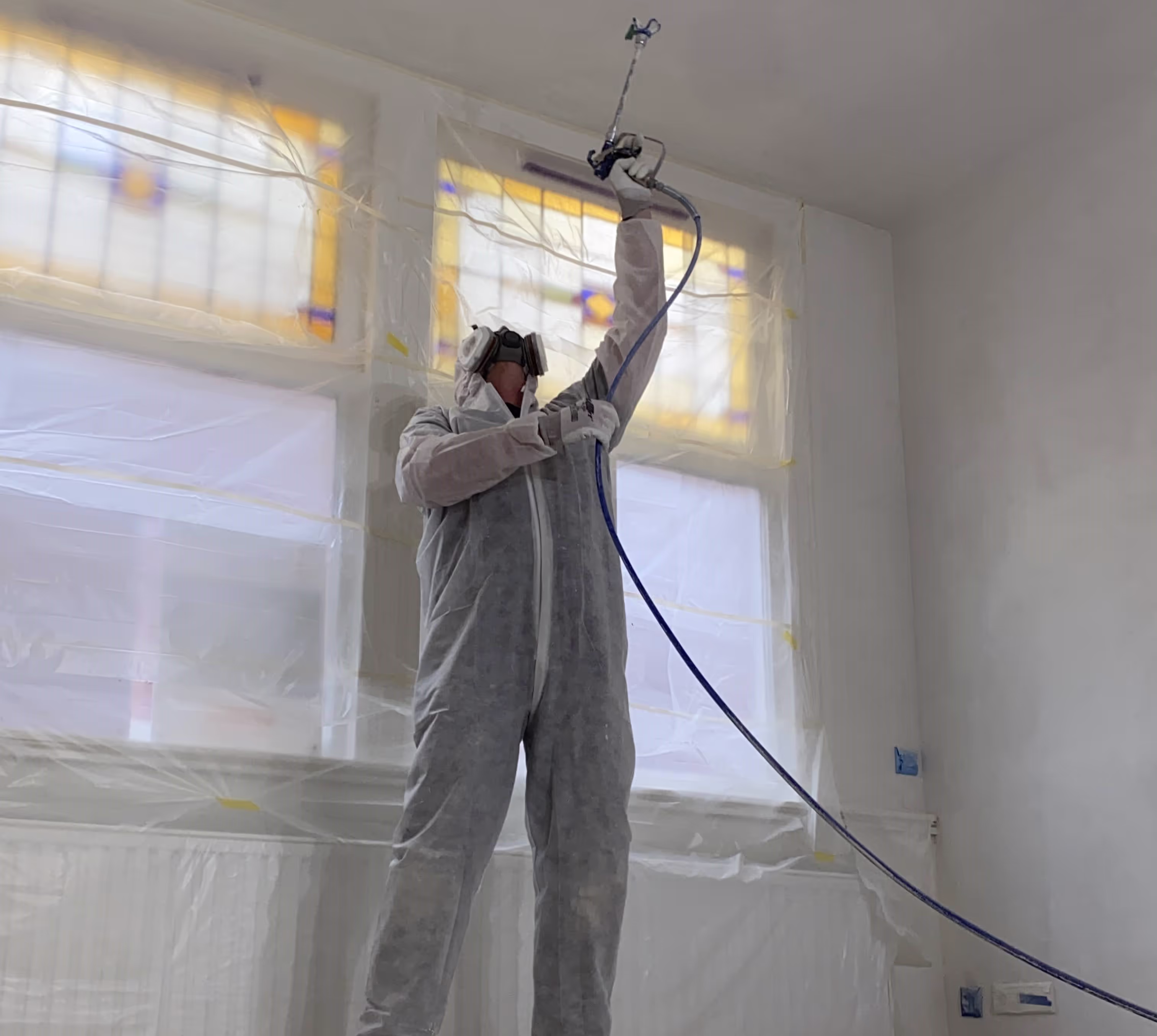 Man in wit pak spuit een plafond